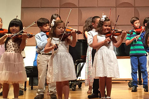 Children performing with violins at the Frost Preparatory Program
